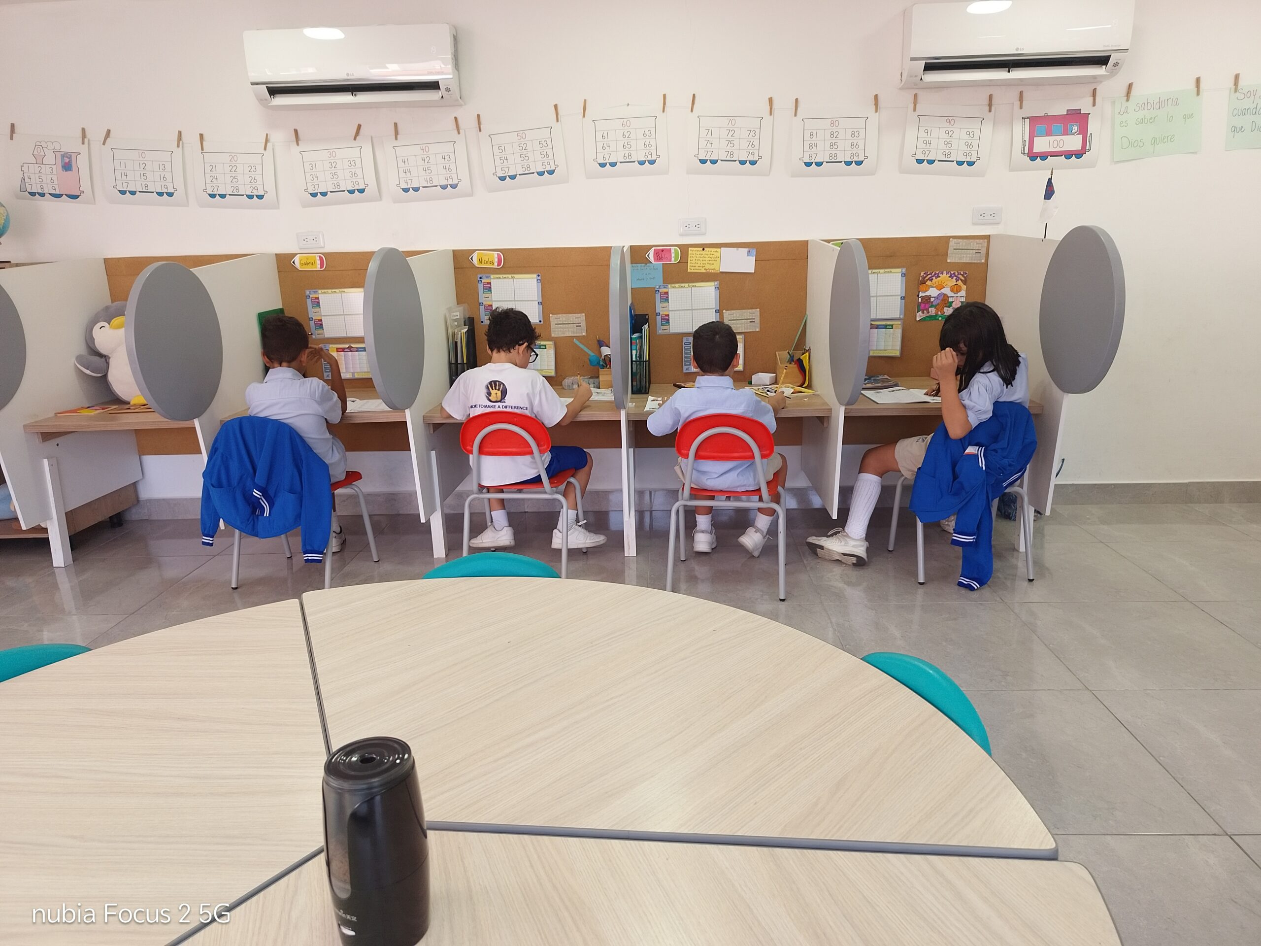 Estudiantes de los primeros niveles resolviendo su material alrededor de la mesa de trabajo