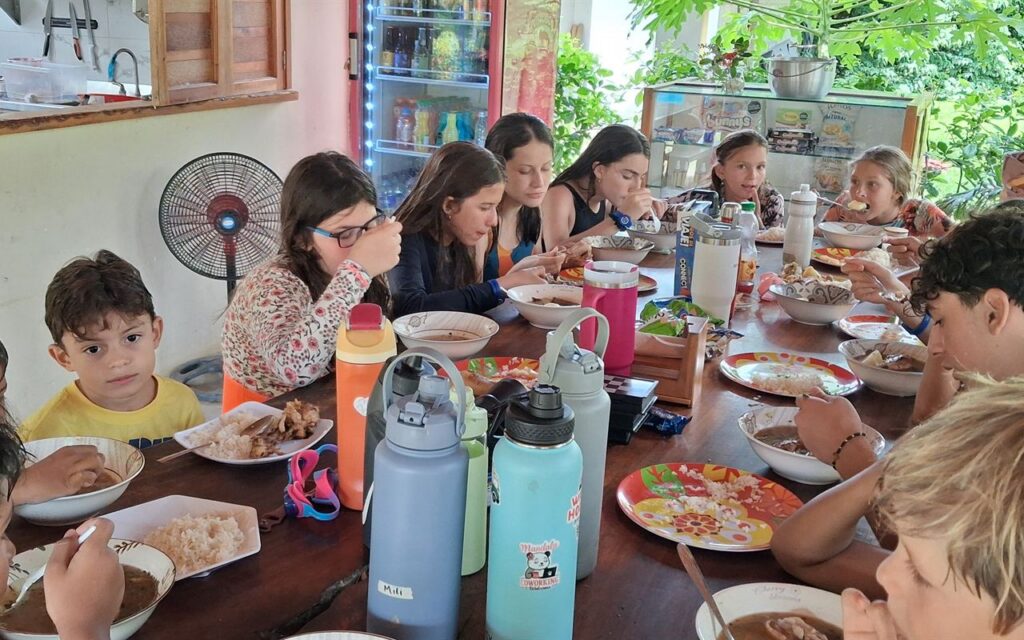 Estudiantes y acompañantes compartiendo una comida en una mesa larga